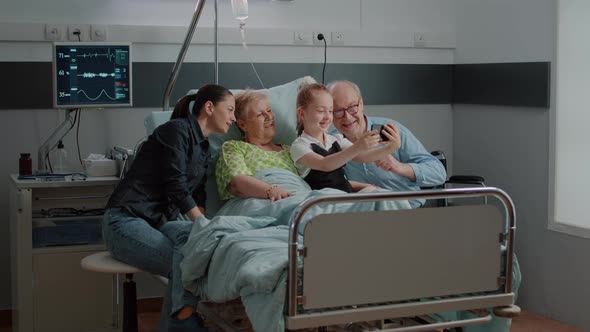 Kid Taking Selfie on Smartphone with Ill Patient and Family at Visit