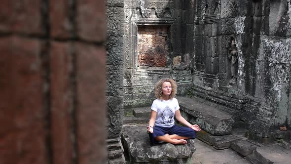 Young Female Meditating In Lotus Pose in Ancient Temple Of Angkor Wat