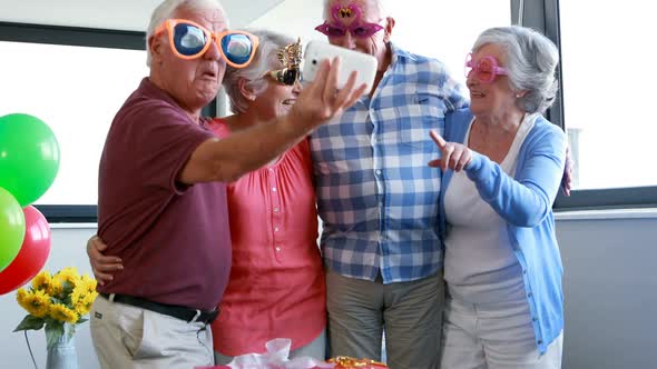 Senior citizens taking selfie on mobile phone during birthday party