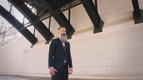 Portrait of Handsome Bearded Mature Man in Suit Outdoors on Modern Building Background During Sunny