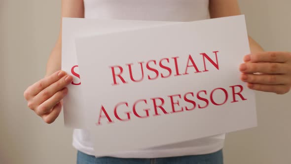 Close Up of a Protester Hands Holding Cardboard Banner with the Words Russian Aggressor Stop War