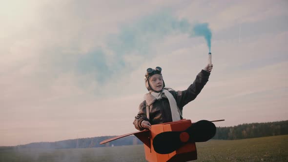 Little Pilot Girl Running, Wearing Fun Cardboard Plane Costume with Blue Colour Smoke on Autumn