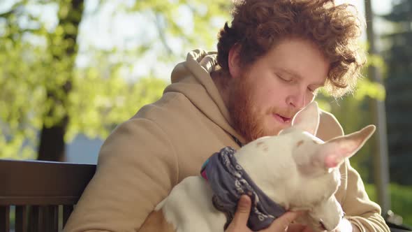 Joyous Man Petting and Giving Snacks to Dog in Park