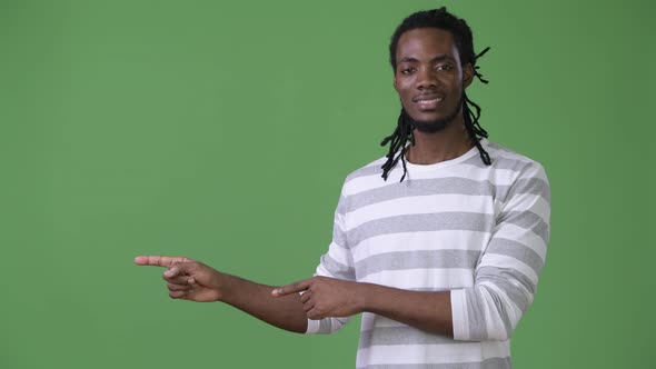 Young Handsome African Man with Dreadlocks Against Green Background