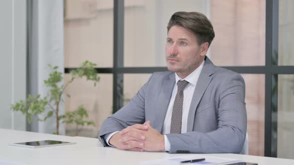 Pensive Middle Aged Man Thinking while Sitting in Office