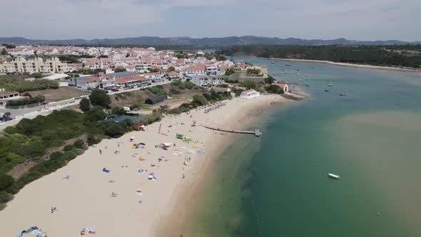 Flyover Pristine Beach towards picturesque white town of Vila Nova de Milfontes, Along Mira River. P