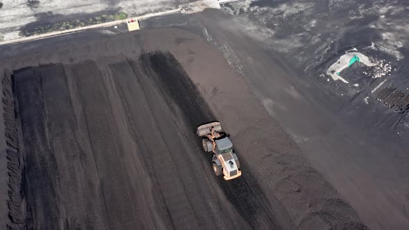 Aerial tracking shot of Digger working on coal mining field and transporting coal