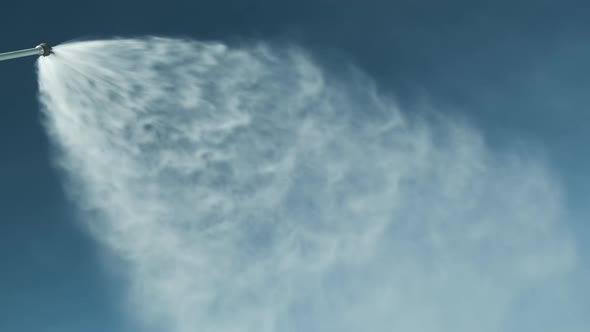 Snowgun Sprays Artificial Snow Against Blue Sky at Ski Resort in Sunny Day