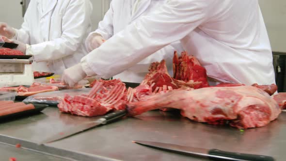 Butchers packing and checking the weight of meat at meat factory