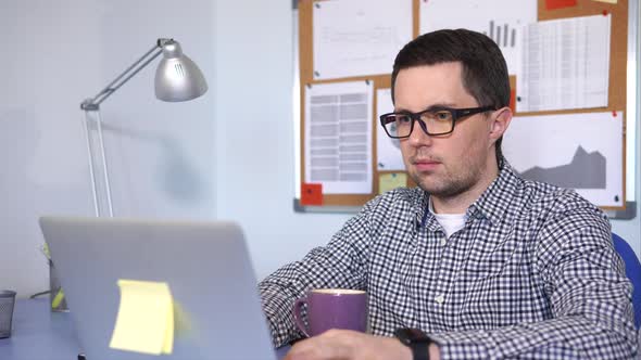 The Manager Typing Text on the Laptop Sitting at His Working Place.