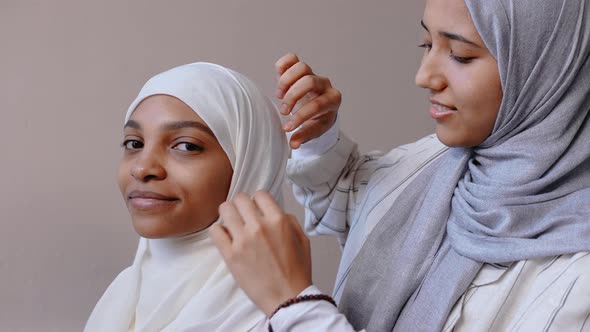 Muslim Girls Adjusting Hijab and Smile in Beige Studio Getting Ready Somewhere