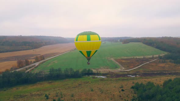 Aerial Drone View of Balloon Flight on a Cloudy Day. A Balloon Flying Low Above the Ground. Autumn