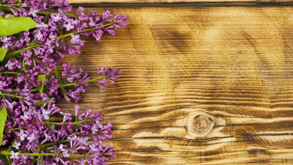 Bouquet of Lilac Flowers Lie on an Old Burnt Wooden Background