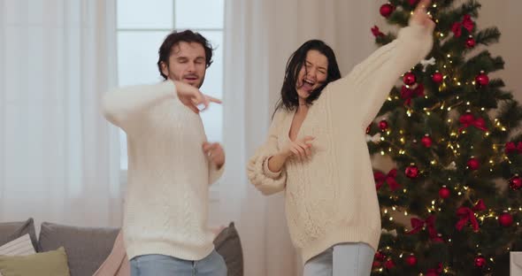 Funny Dancing Couple Celebrating New Year Near Christmas Tree at Home