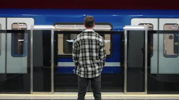 Back View of Young Man Waits for a Train in the Subway a Student Goes to Study at the University