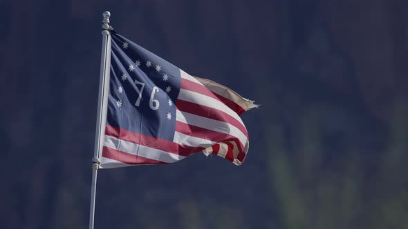 American 76 flag flapping in slow motion in front of mountains old west