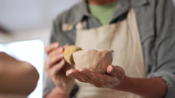 Potter smoothing the walls of the clay bowl