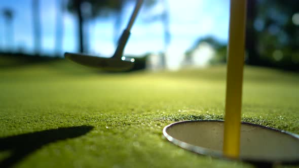 Mini Golf Yellow Ball with a Bat near the Hole at Sunset