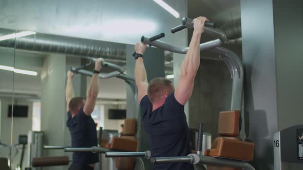 Muscular Man Performing Pull-ups in Fitness Club