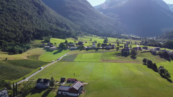 Green farmland fields in Lodalen Nordfjord Norway - Forward moving aerial besides road fv723 and aga