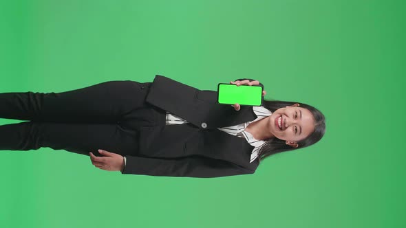 Asian Business Woman With A Smile Showing Green Screen Mobile Phone While Standing On Green Screen