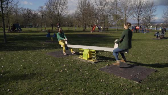 Couple playing together at seesaw in public playground, Zagreb, Croatia.