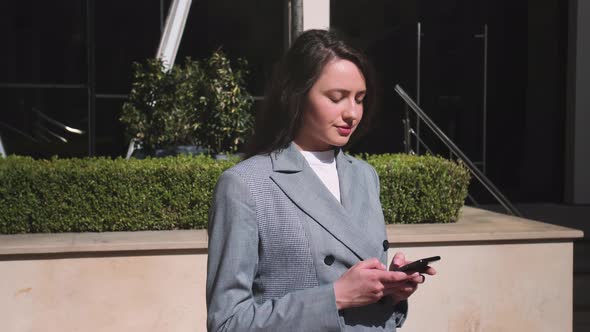 Pretty Smiling Woman Typing on Phone in the Street