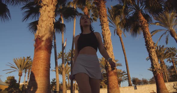 Woman Walking Through Trees On Beach