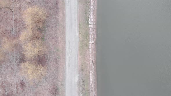 Empty road along river. Aerial top view of pedestrian tourist path along lake.