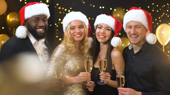 Smiling Colleagues in Santa Hats Clinking Champagne Glasses, Corporate Event