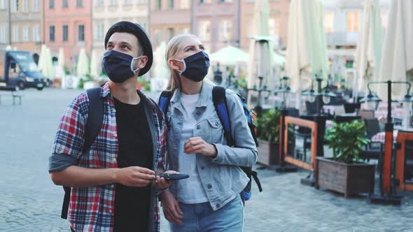 Tourists in Protective Masks and with Bags Using Smartphone