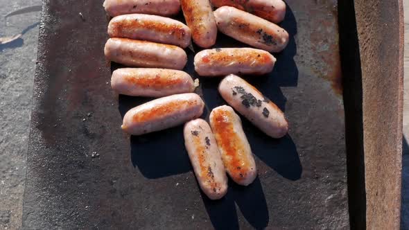 Pork sausages cooking on an open fire barbecue. SLOW MOTION, TOP DOWN