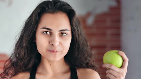 Closeup Face of Hungry Beautiful Young Girl Having Perfect Skin Eating Apple Looking at Camera