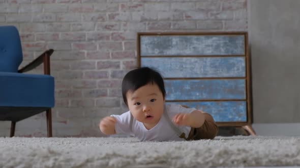 Happy inquisitive baby crawls on floor of room for camera