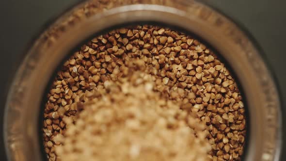 TOP VIEW: Buckwheat Grains Pouring Into A Glass Jar - Slow Motion