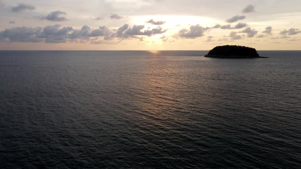 Aerial Flying Over Calm Sea During Golden Sunset With Silhouette Of Island In Background. Dolly Forw