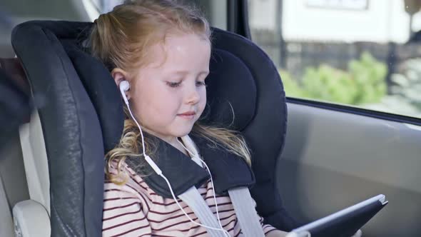 Beautiful Girl Watching Cartoon on Tablet in Backseat