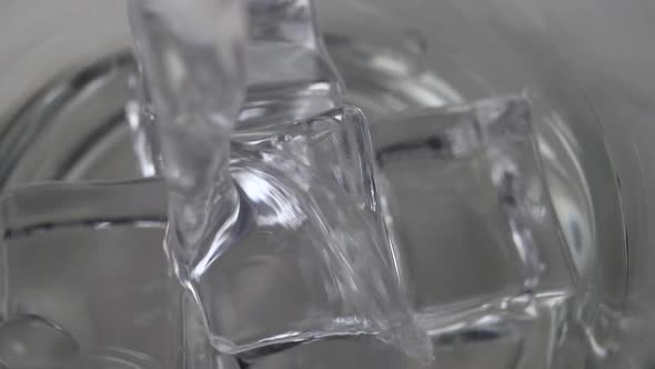 Fresh spring water is poured onto ice cubes in a glass. 