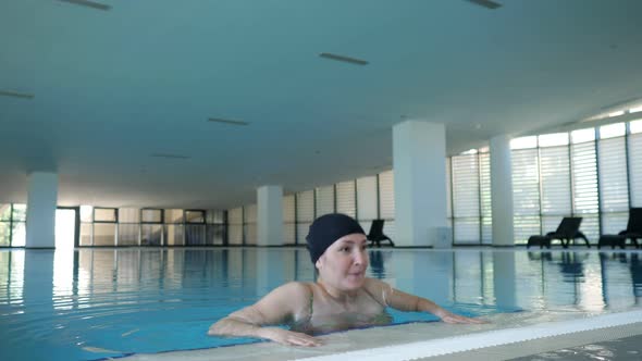 Happy Woman in Cap Climbs Out the Pool and Looks at Camera