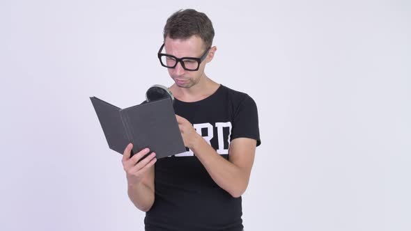 Studio Shot of Nerd Man Reading Book with Magnifying Glass