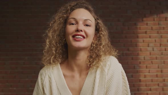 POV of a Young Smiling Curly Caucasian Woman Greeting Her Friends on a Video Call on Her Laptop