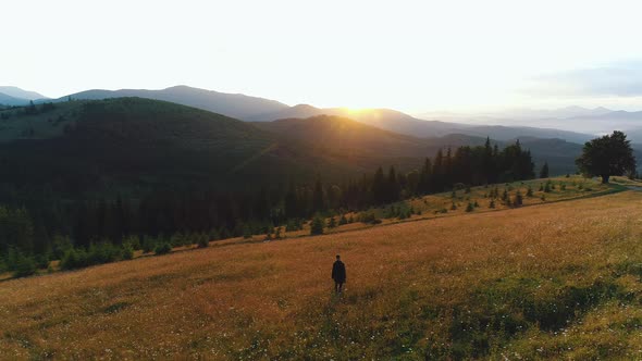 a Guy Walks in a Valley of Mountains