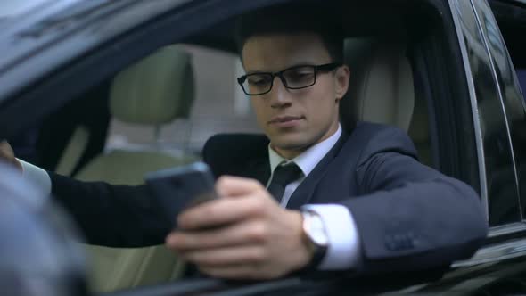 Happy Businessman Texting With Girlfriend and Smiling While Sitting in Car