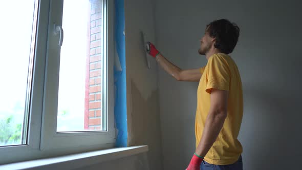 A Young Man in a Yellow Tshirt is Doing a Walls Renovation in His Home