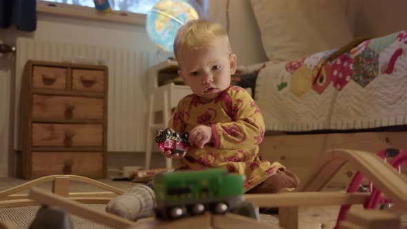 ZOOM IN - cute baby watching a toy train before managing to catch and study it