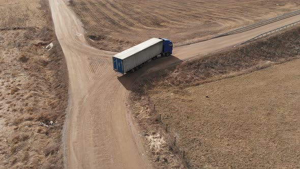 Aerial View of a Large Truck with a Trailer Driving Along a Dirt Road in Search of a Place for a U