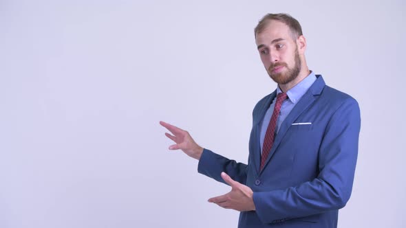 Happy Bearded Businessman Presenting Something To the Back