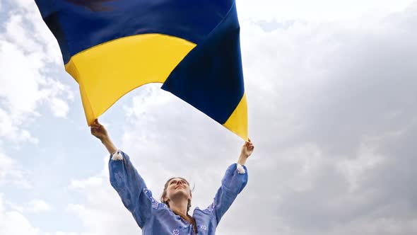 Smiling Ukrainian Woman with National Flag on Sky Background