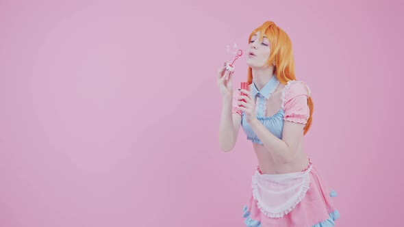 Studio Shot of A Young Kawaii Girl That Blows Soap Bubbles Pink Background