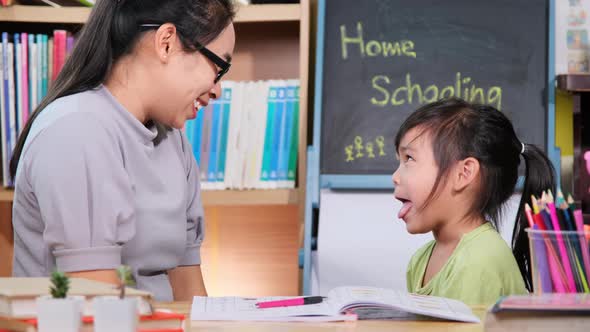 Asian little girl studies at home during quarantine with her mother. alt